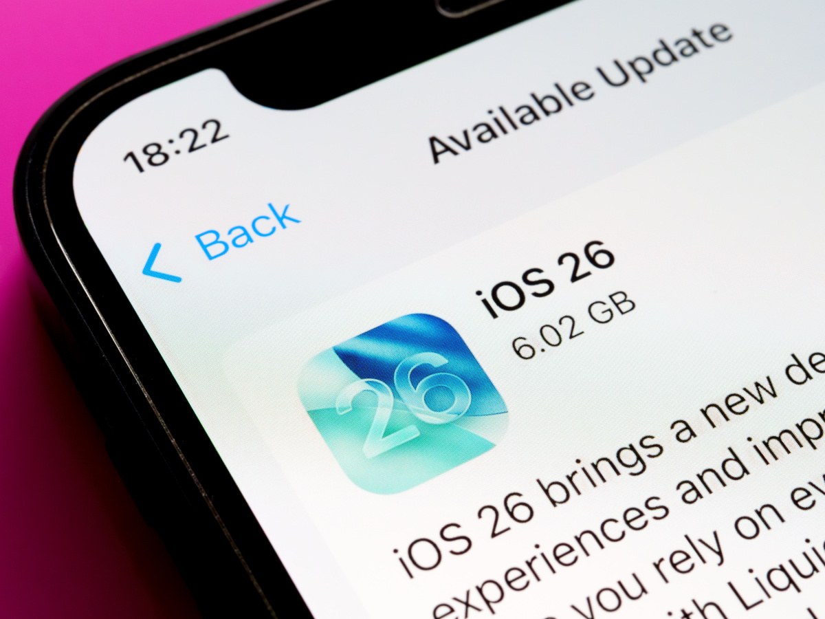 iOS 26 update icon and text on iPhone with pink backdrop.