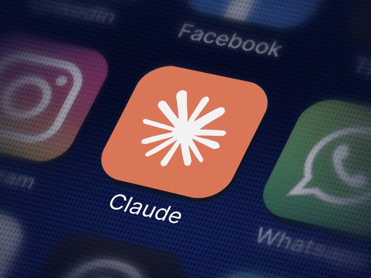 The Claude app, an orange background with a white Claude logo, on a smartphone screen.