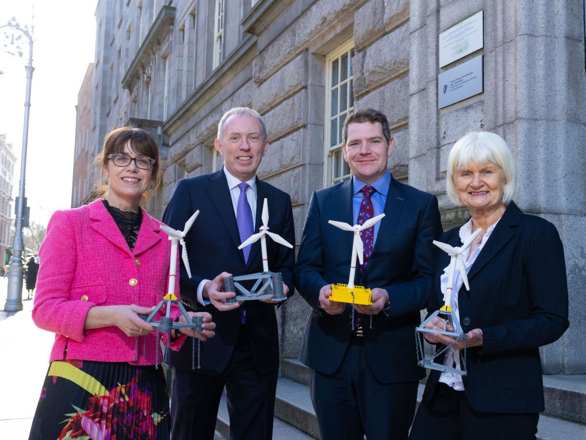 Four people holding miniature models of wind turbines standing in a Dublin neighbourhood.