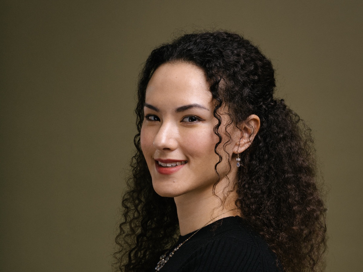 A woman with dark hair looks to camera smiling