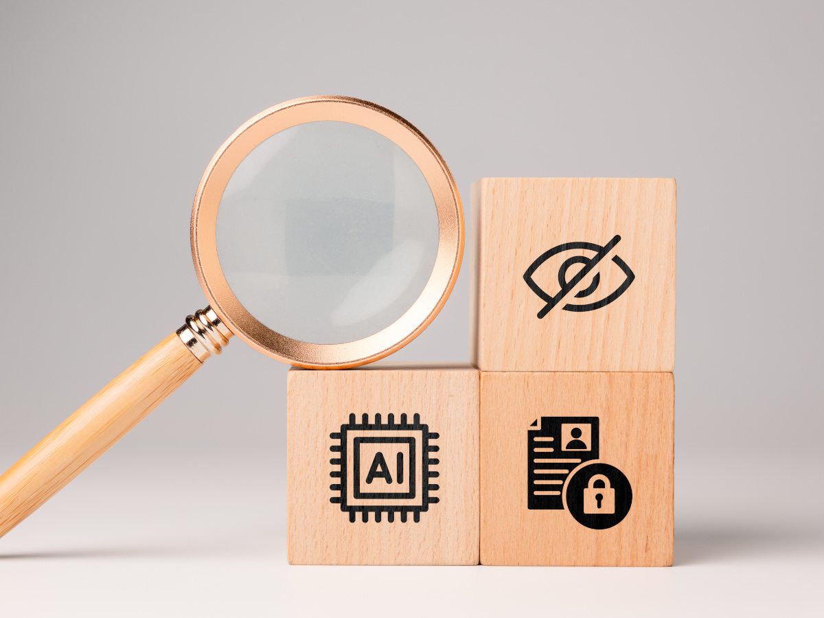 A magnifying glass next to three wooden blocks representing policy, AI and privacy.