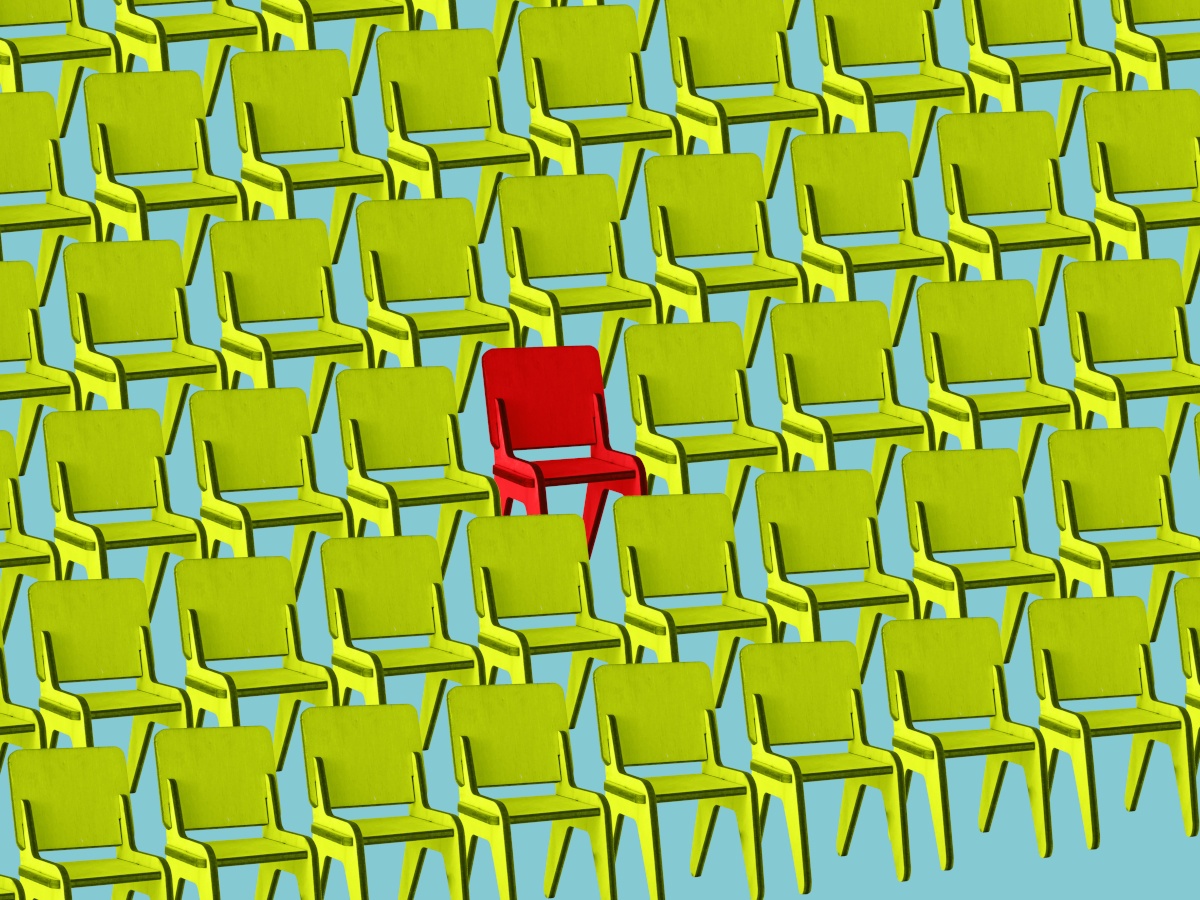 Several rows of green chairs with one red chair signifying layoffs.