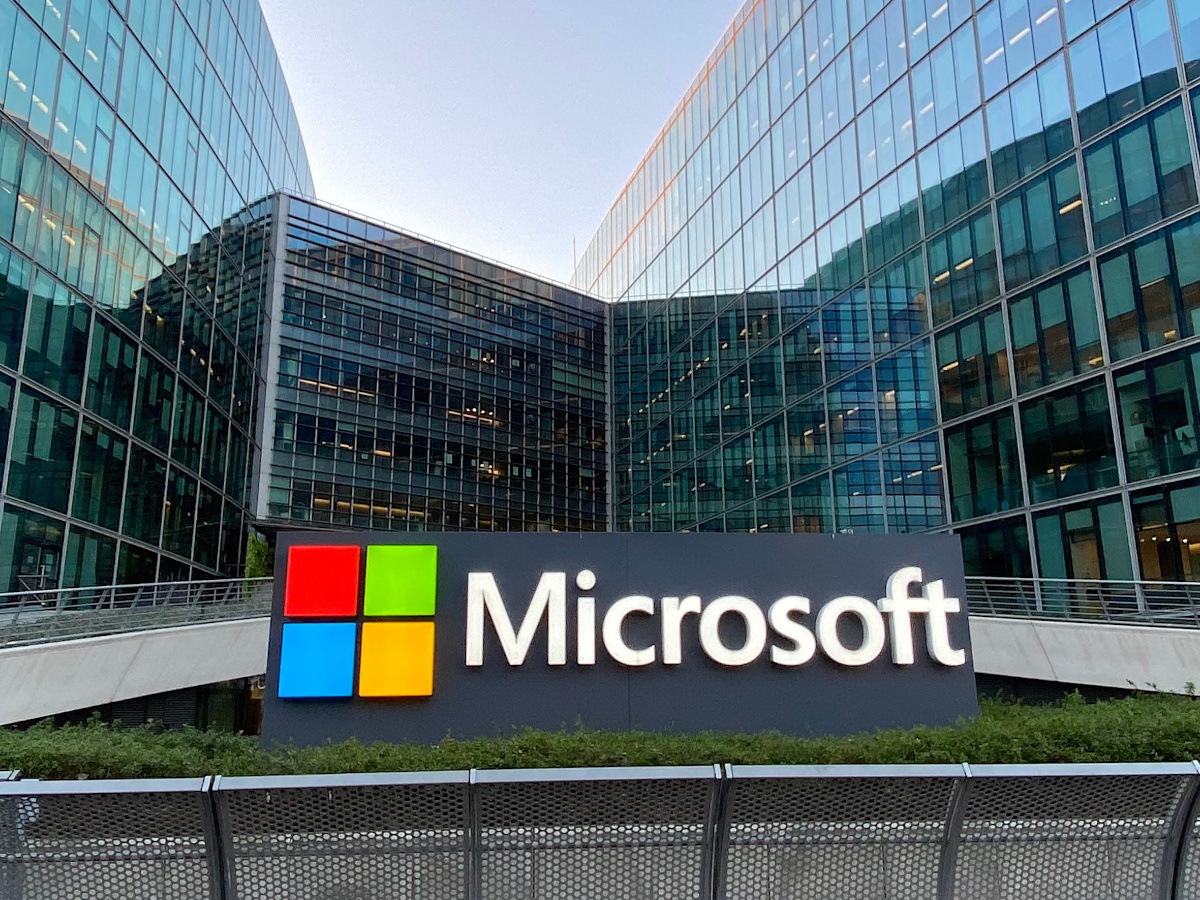 The Microsoft logo outside a glass building.