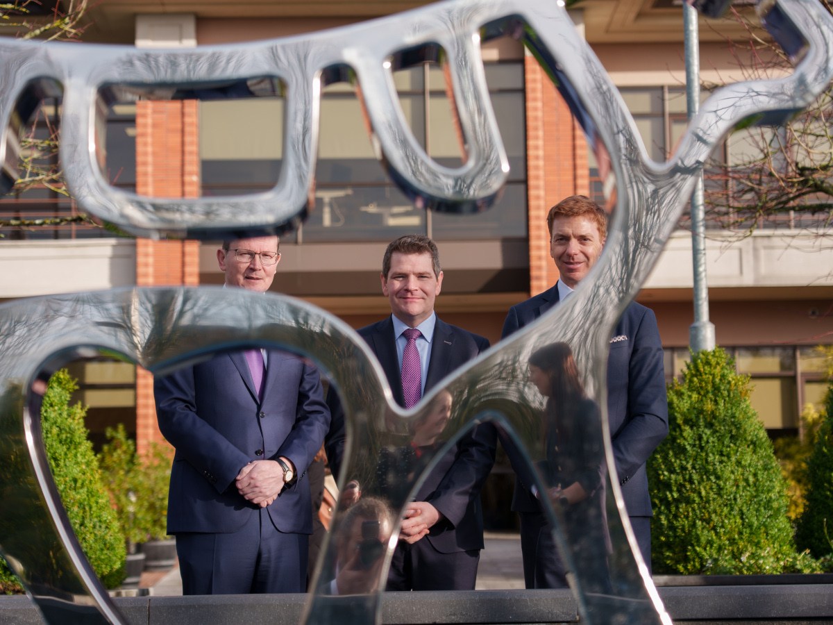 Three men in suits standing behind a Novo Nordisk logo made out of metal.