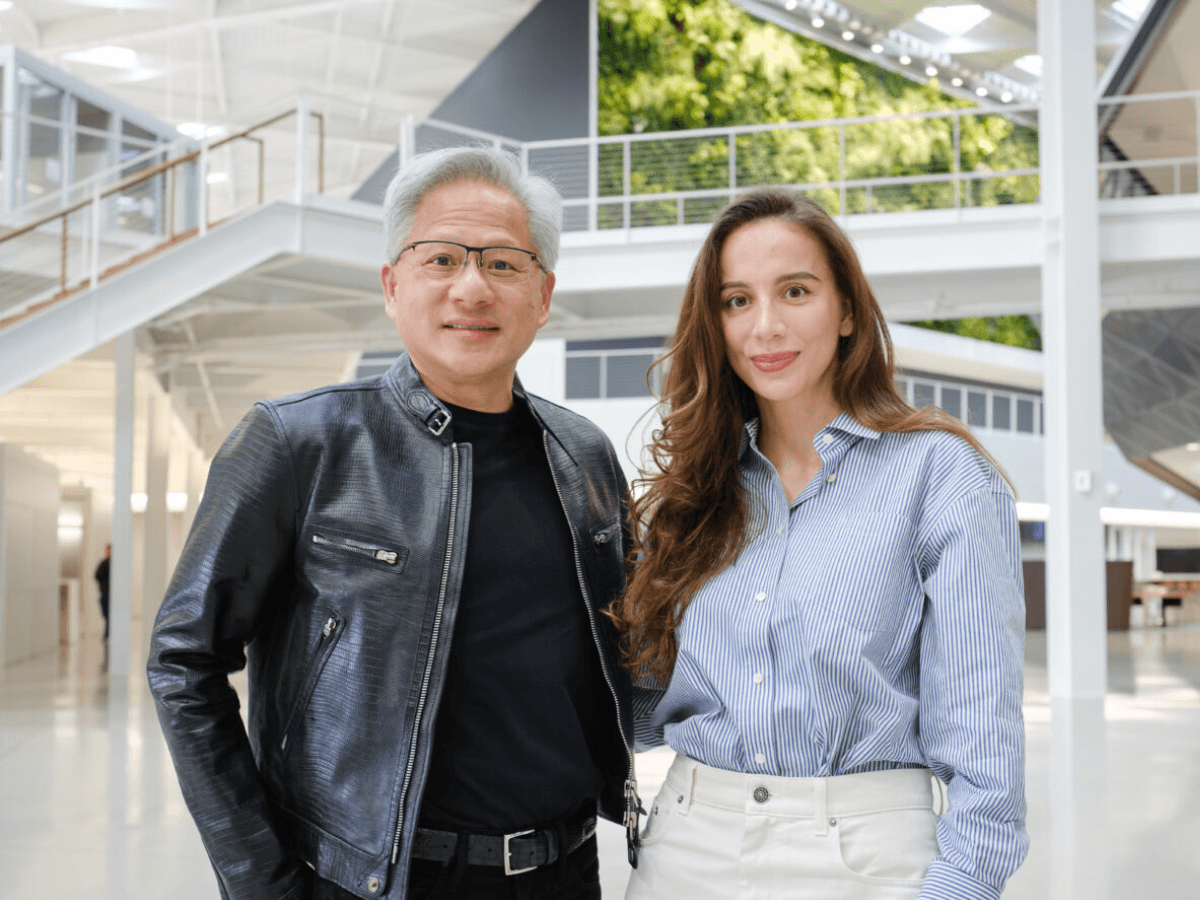 A man in a leather jacket with glasses standing next to a woman with long brown hair wearing a light blue shirt.