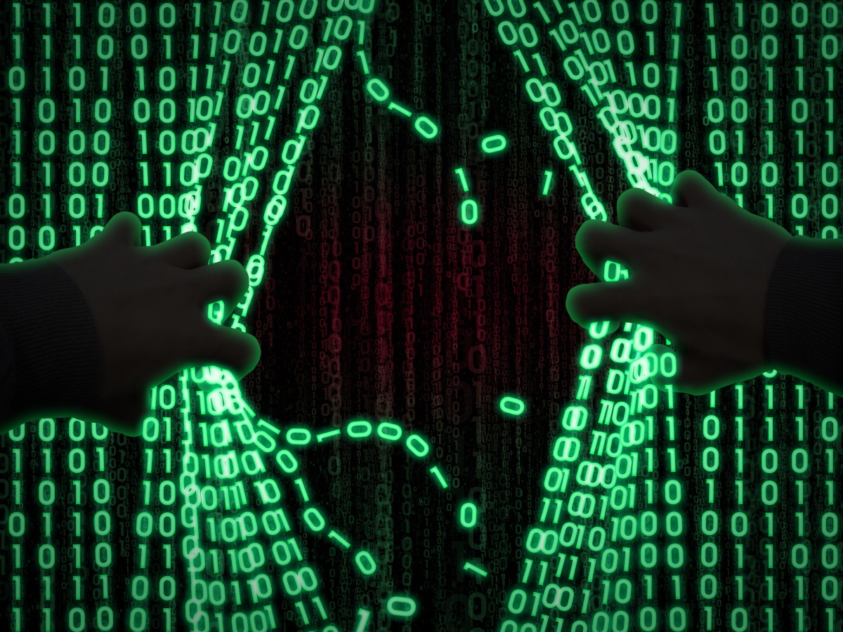 A pair of silhouetted hands pulling back strings of green binary code.