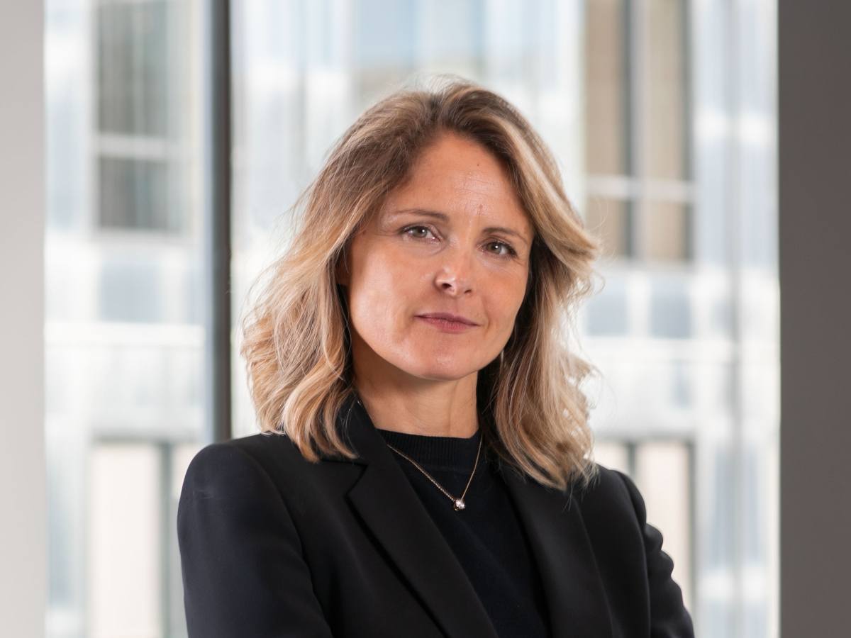 Woman in suit looks to camera.