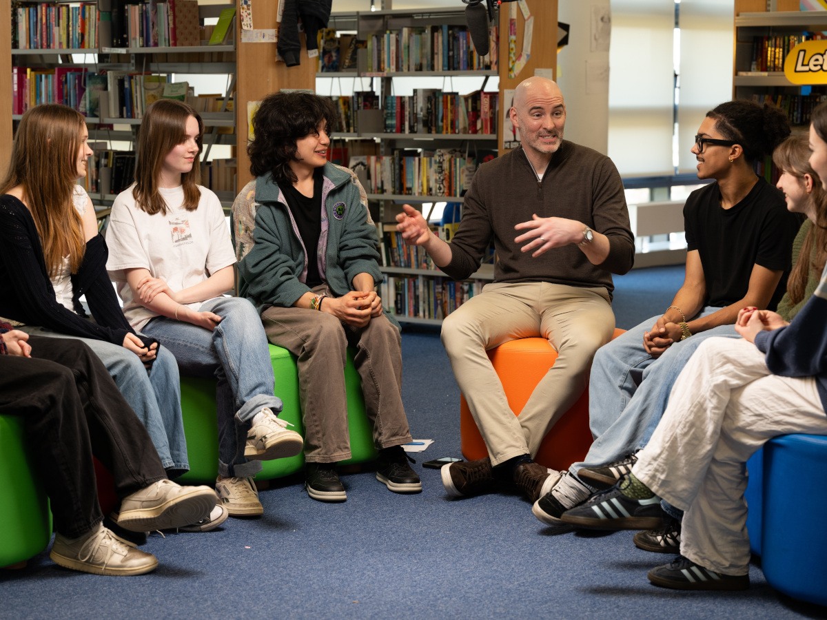 A middle-aged white man surrounded by a diverse group of young people discussing SPHE reform.