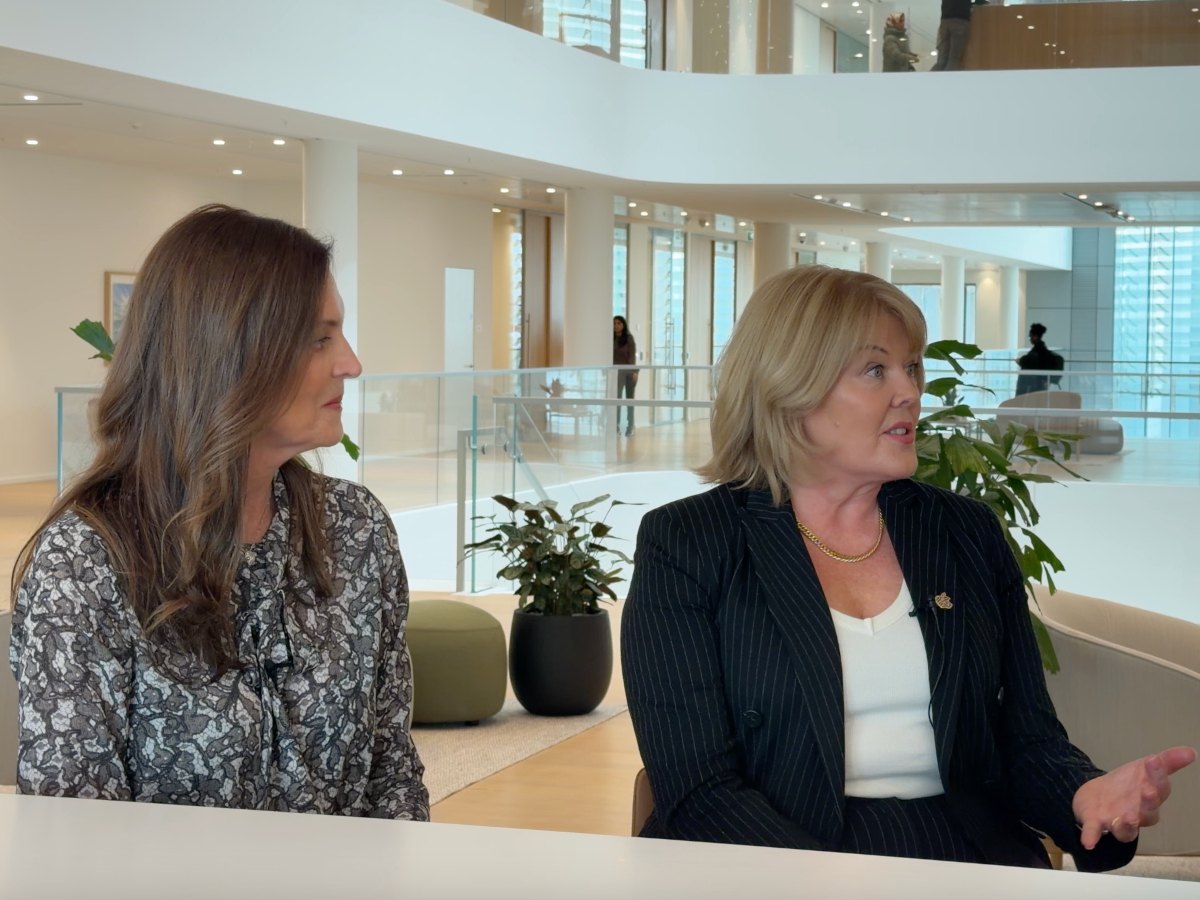 Two women with modern office backdrop.
