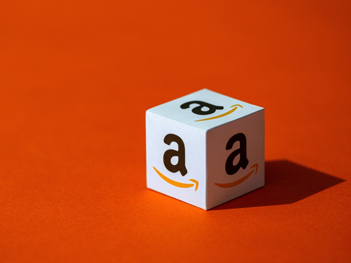 The Amazon logo on a white dice against an orange background.