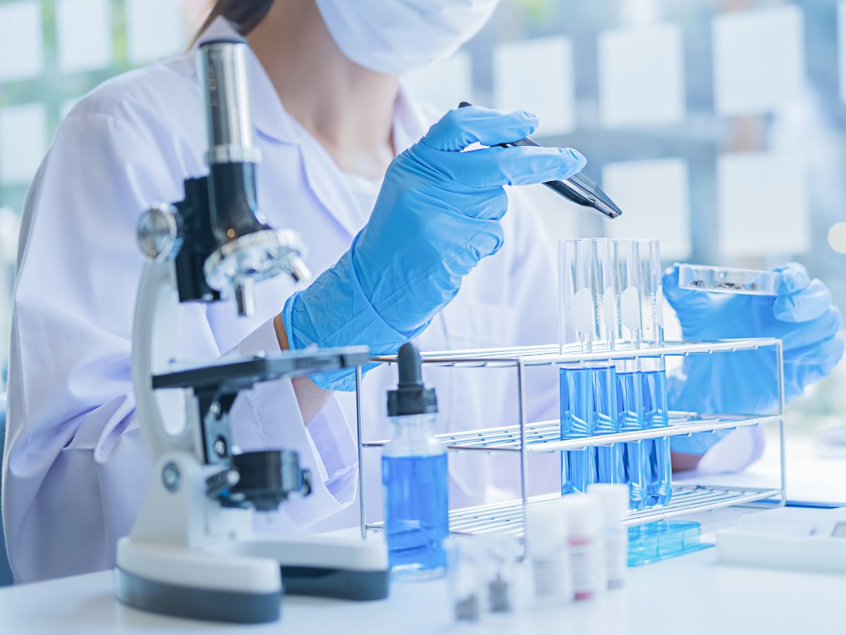 A female lab assistant in lab gear working on an experiment