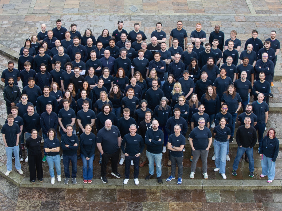 A large group of people with dark blue hoodies looking up.