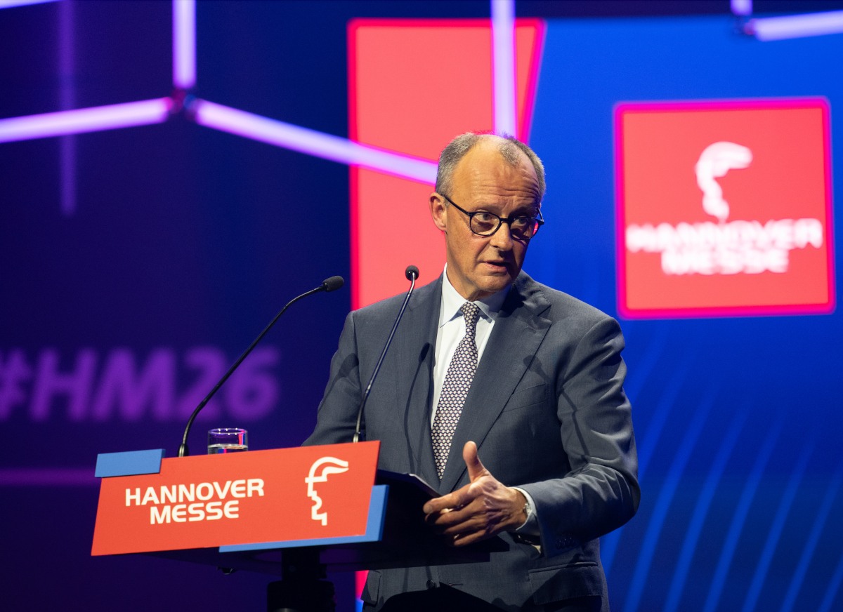 Man stands at dais with Hnnover Messe logo behind