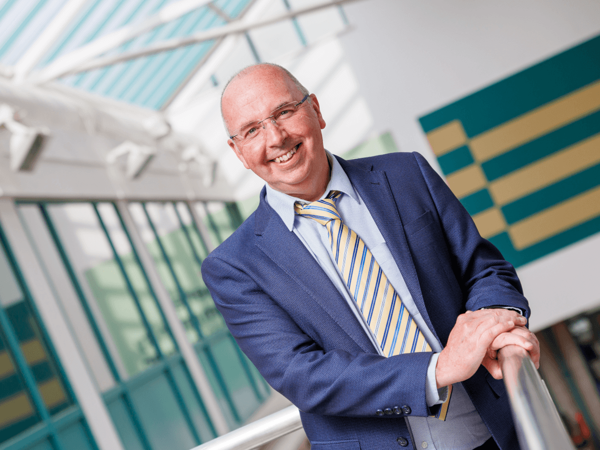 A bald man in a blue suit smiling at the camera.