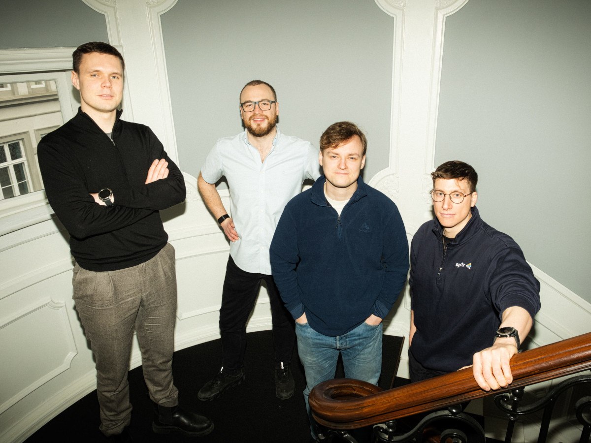 Four white men pose for the camera in casual clothing.