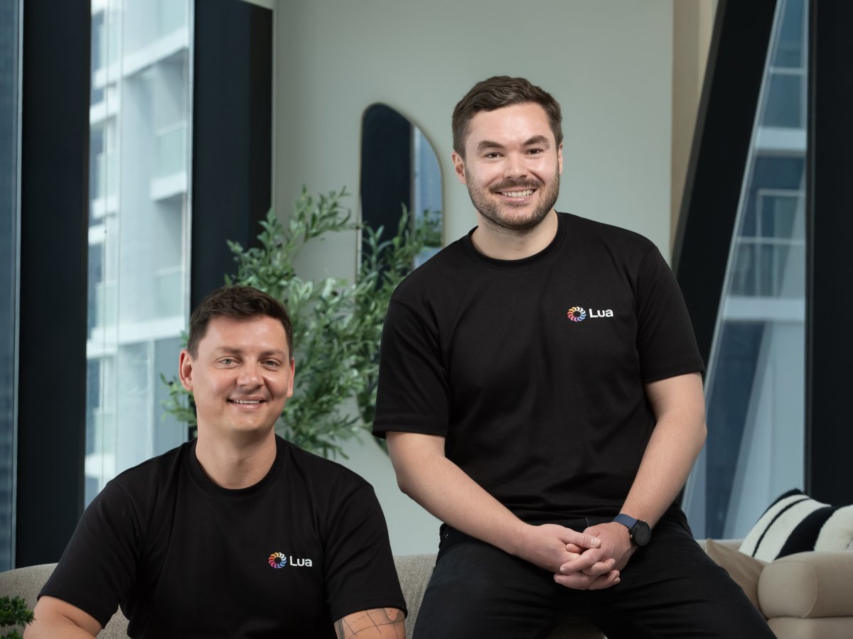 Two young white men in black, Lua-branded t-shirts smile for the camera.