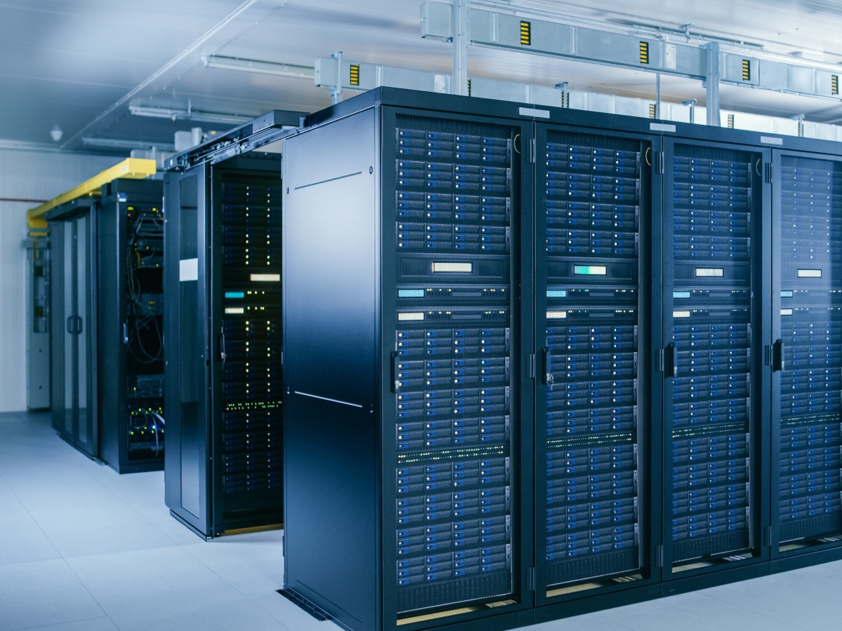 Rows of data centre servers sit in cabinets blinking in a cold blue server room.