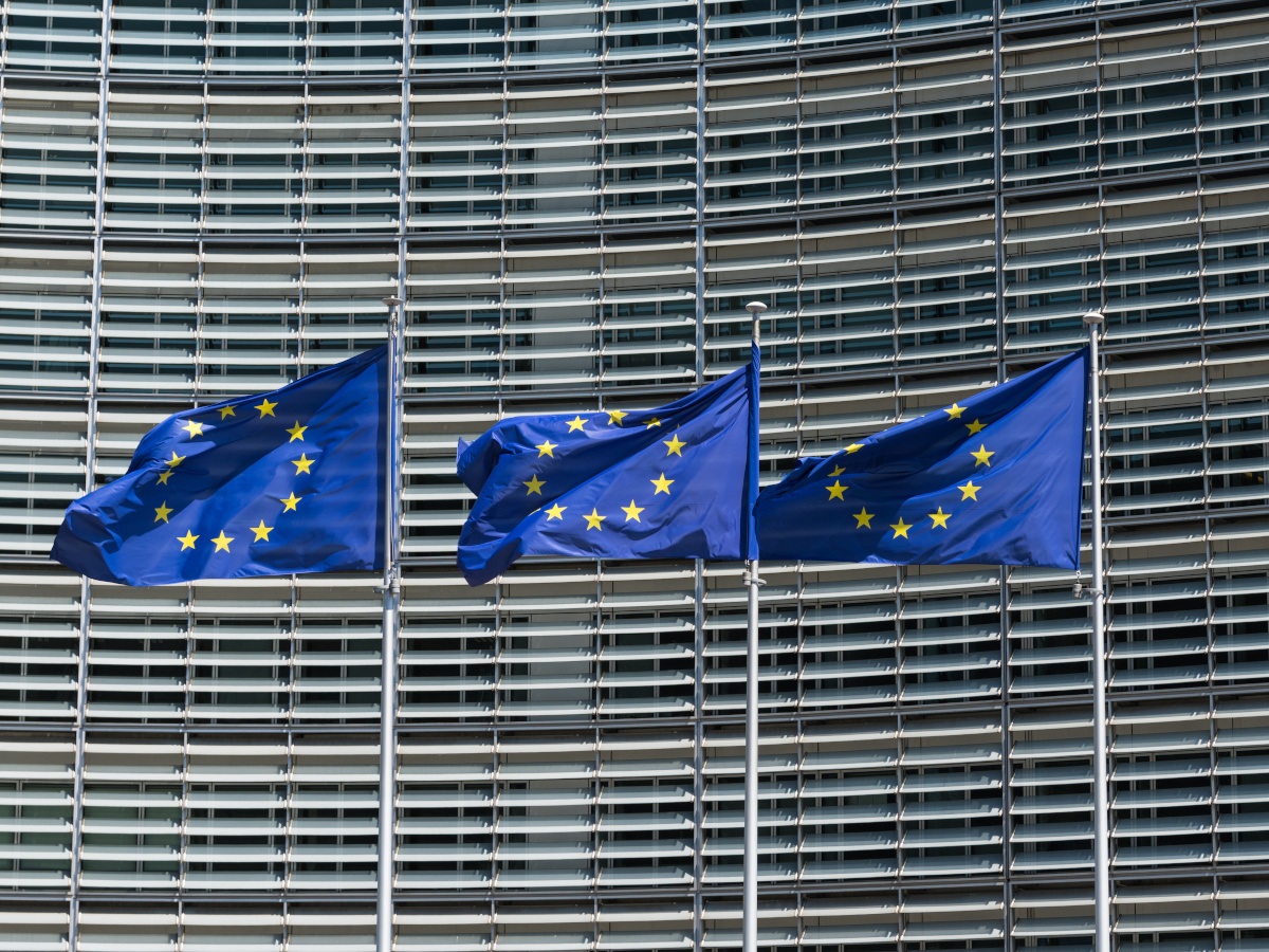 Three European Union flags fluttering in the breeze in front of the European Commission building in Brussels.