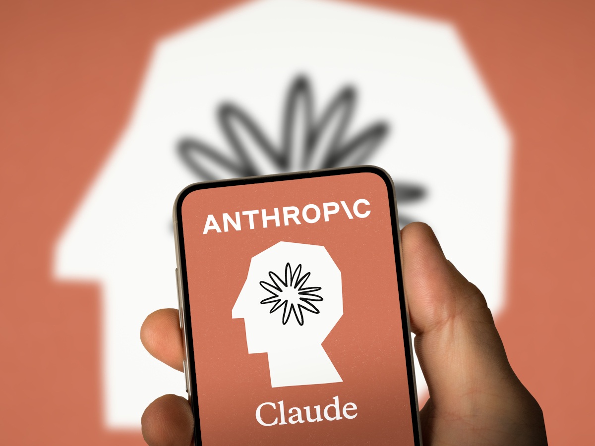 Claude logo in the background and a Claude logo on a smartphone with a hand holding it.