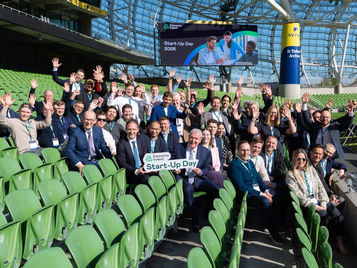 A group of people in suits on green seats at the Aviva stadium on a sunny day. There