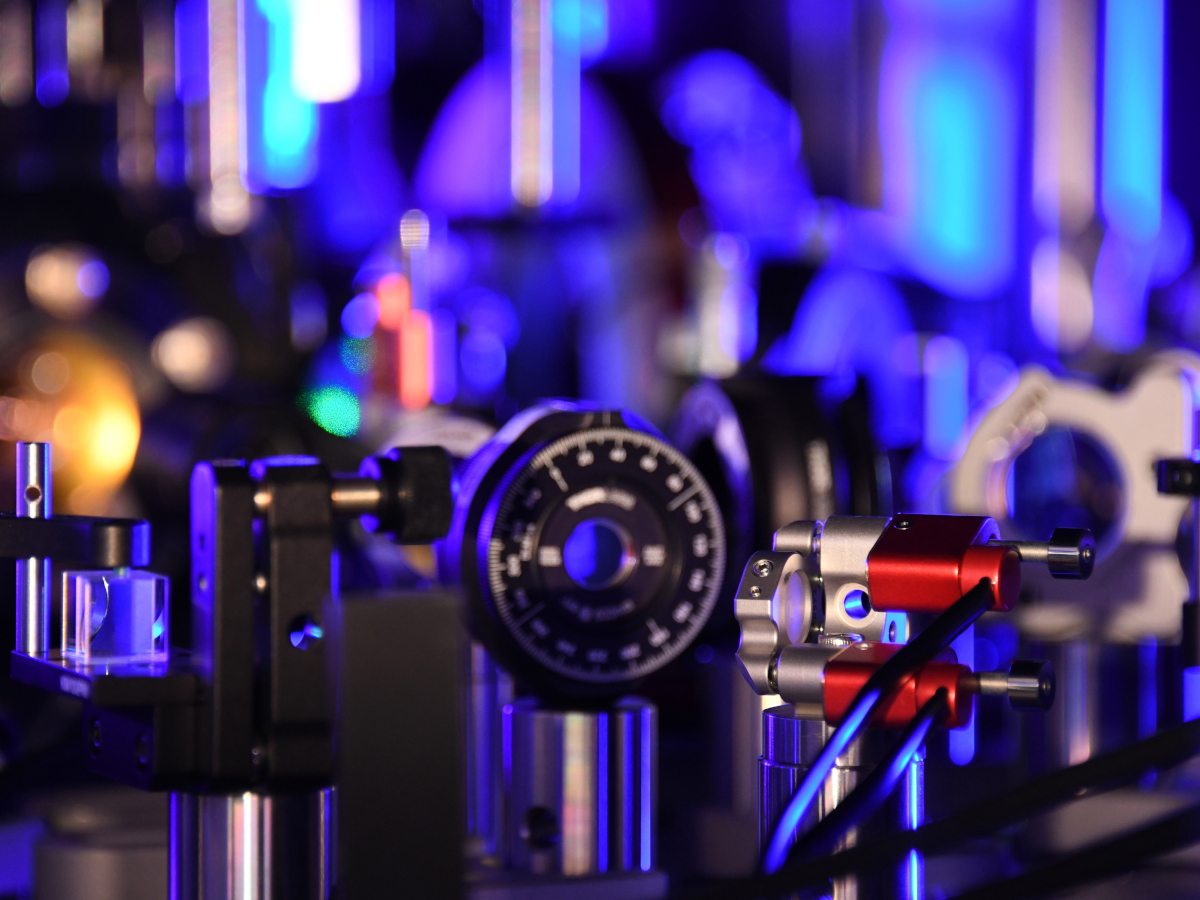 A close-up of small mechanical parts on a flat surface. Much of the background is lit in purple lights and blurred.