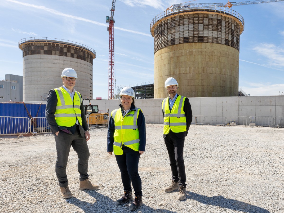 Two men and a woman in high-vis gear pose outside.