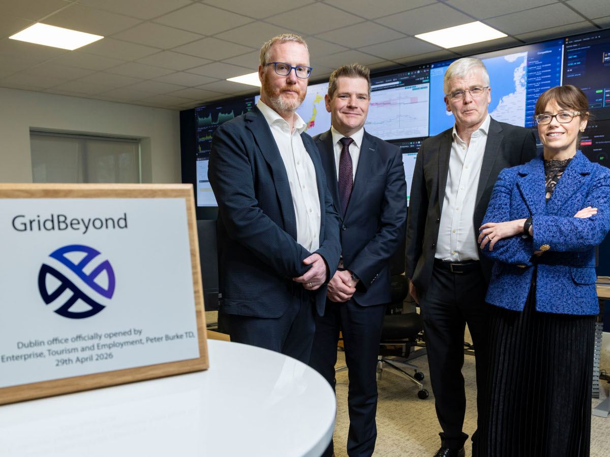 Three white men and one white woman, all middle aged and in business attire, next to a GridBeyond framed imaged.