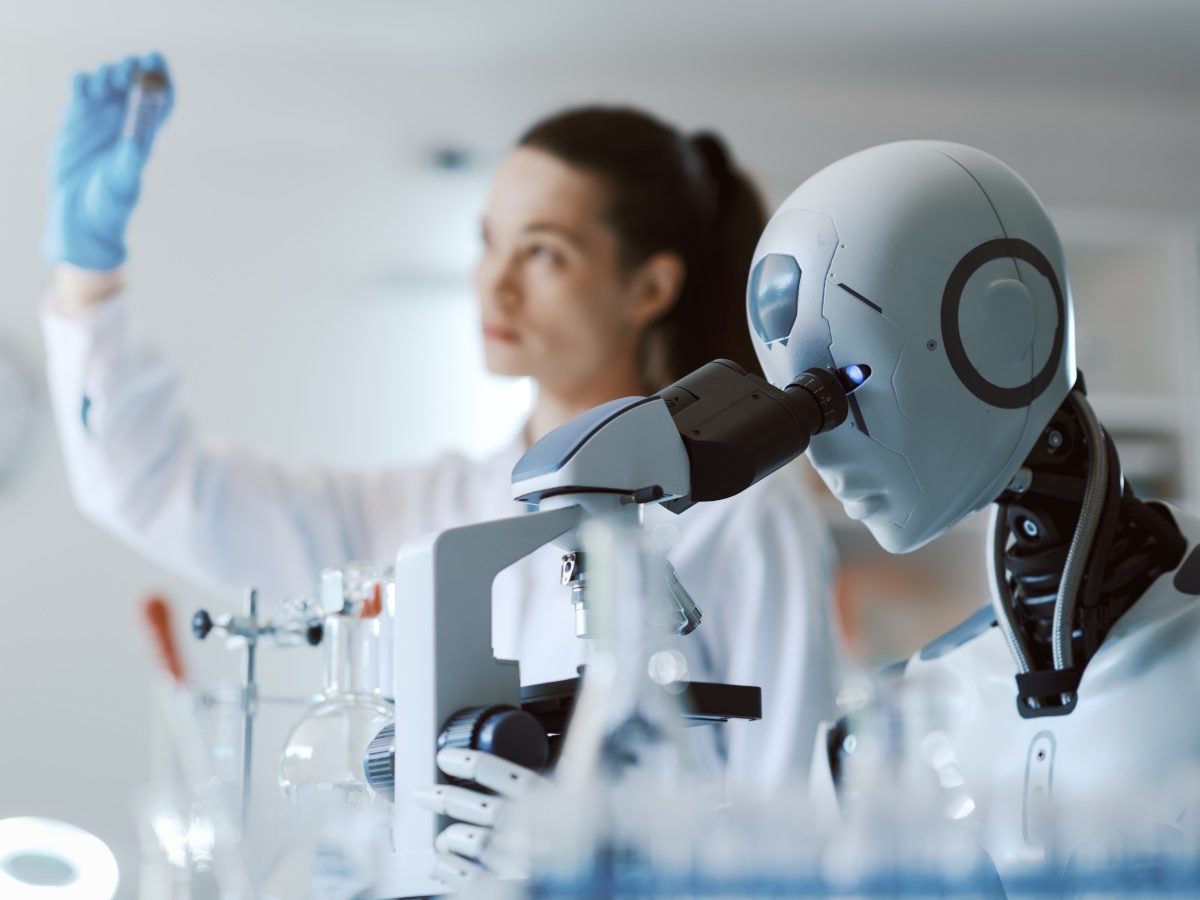 An AI robot looking into a microscope, next to a female scientist holding up an experiment.