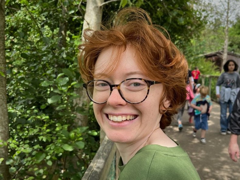 A person with big round glasses and messy reddish blonde hair.