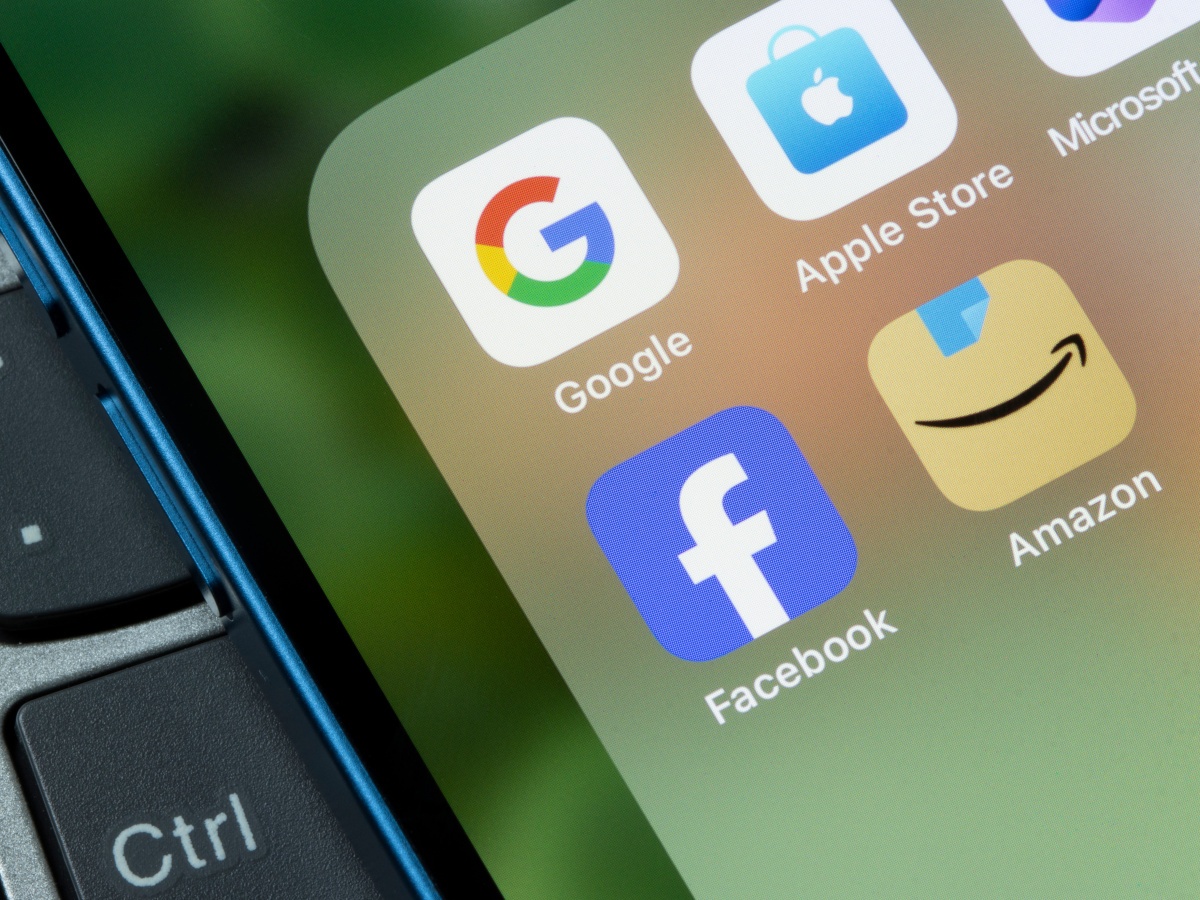 Google, Facebook, Amazon, Apple and Microsoft logos on a smartphone folder.