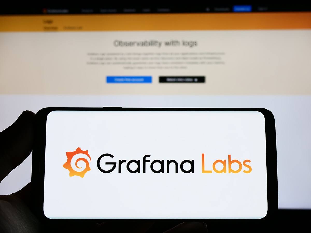 The black and orange Grafana Labs logo on a phone against an open laptop screen.