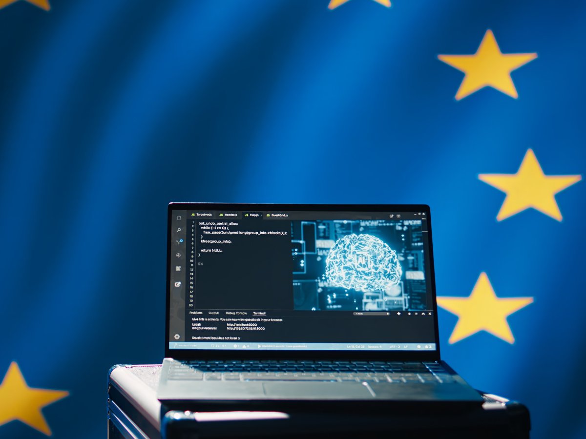 The European flag behind a laptop with organisational AI on it.