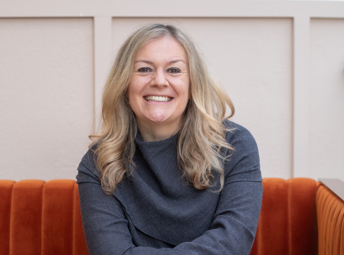caucasian woman with blonde hair, seated, smiling