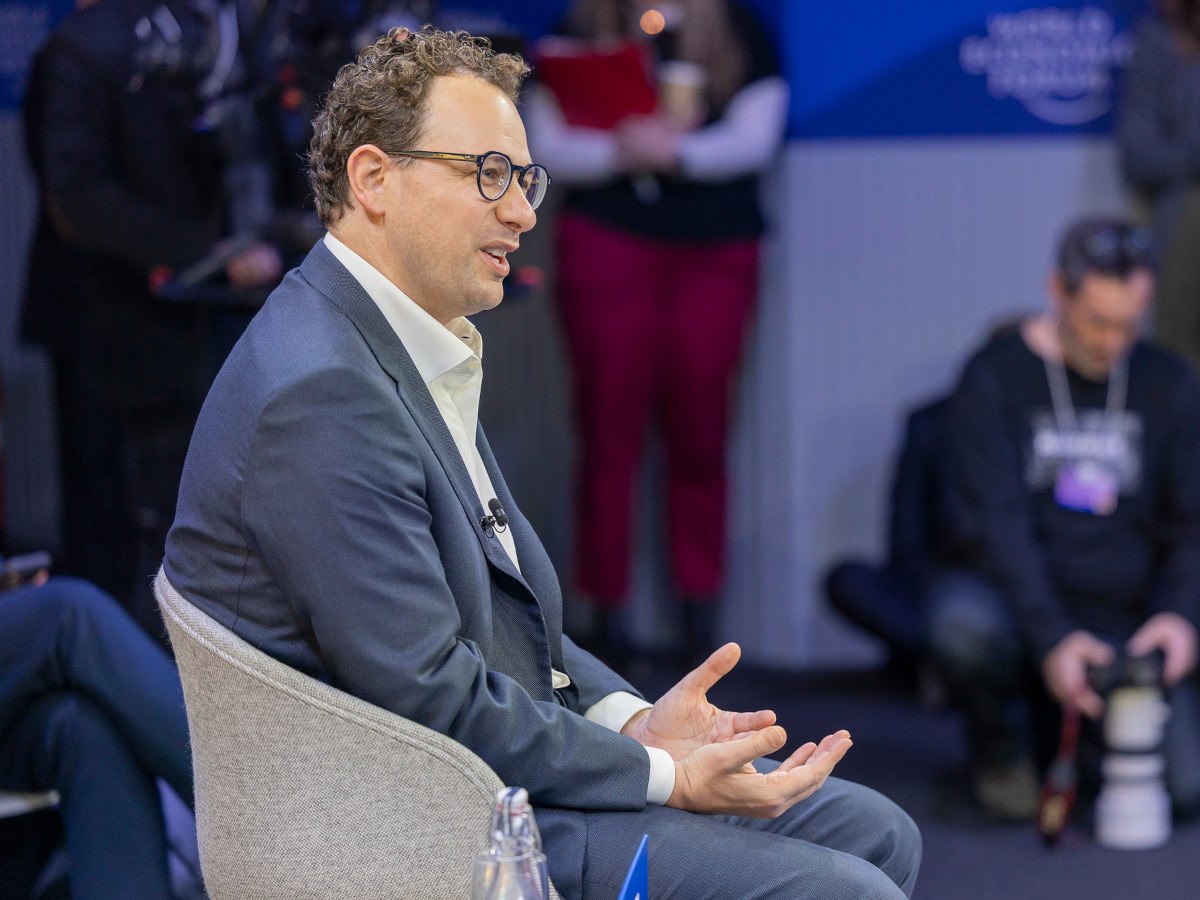 A man in a suit with glasses speaking at a conference.