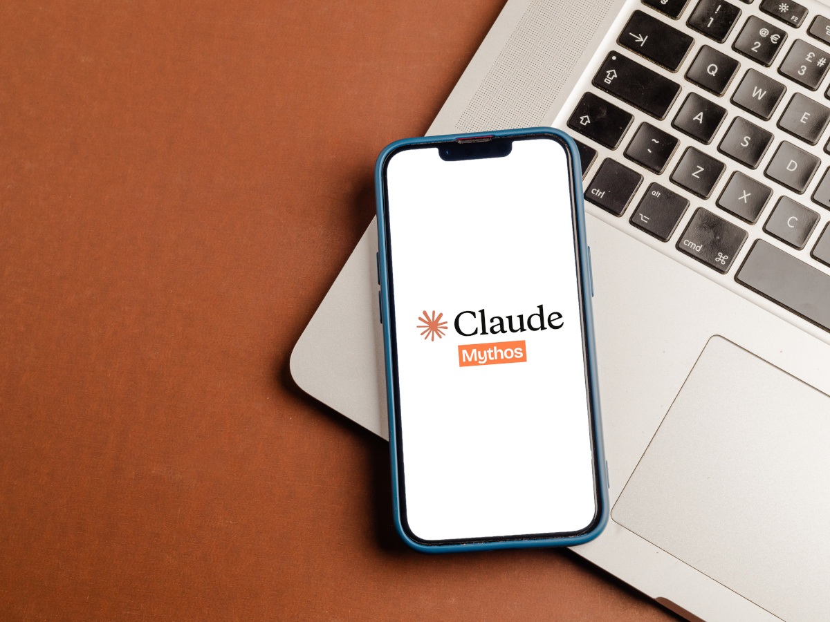 The orange and white Claude logo on a phone against a laptop.