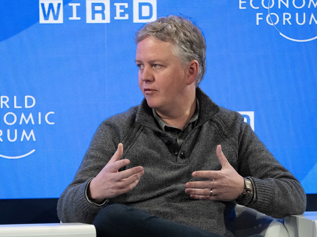 Cloudflare CEO Matthew Prince is seen wearing a grey jumper talking to someone to his side. He has grey hair.