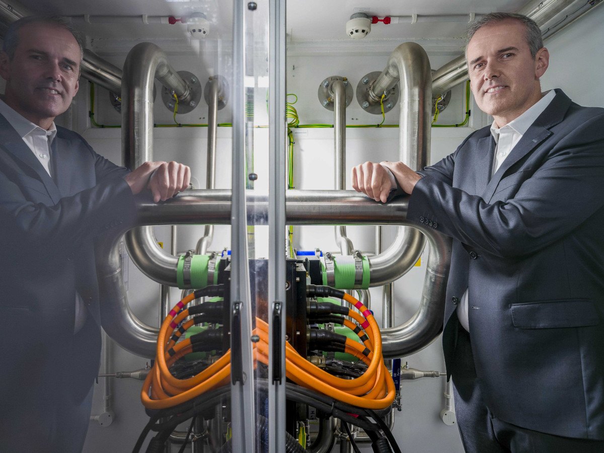 A picture of a man standing next to a hydrogen power machine at a data centre.