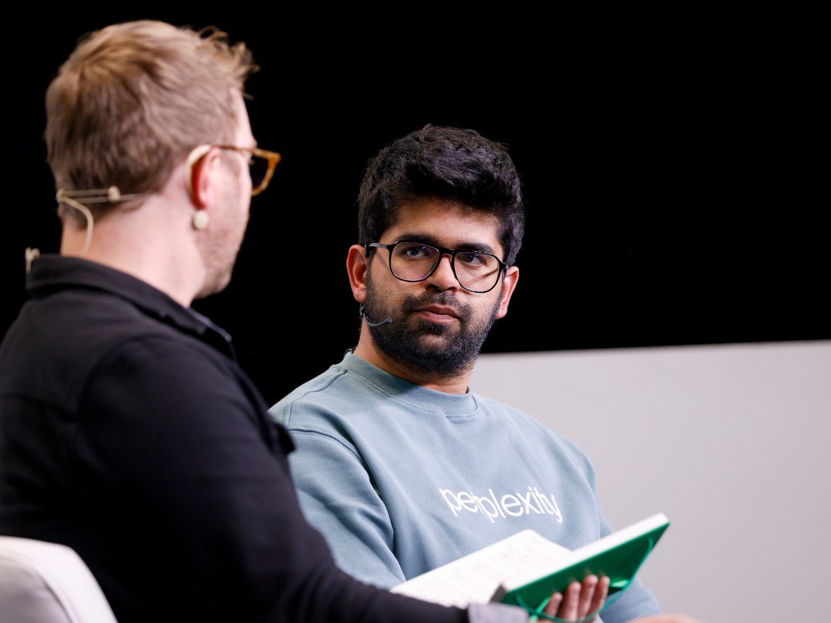 A man with dark hair, glasses and a beard wearing a grey sweat shirt.