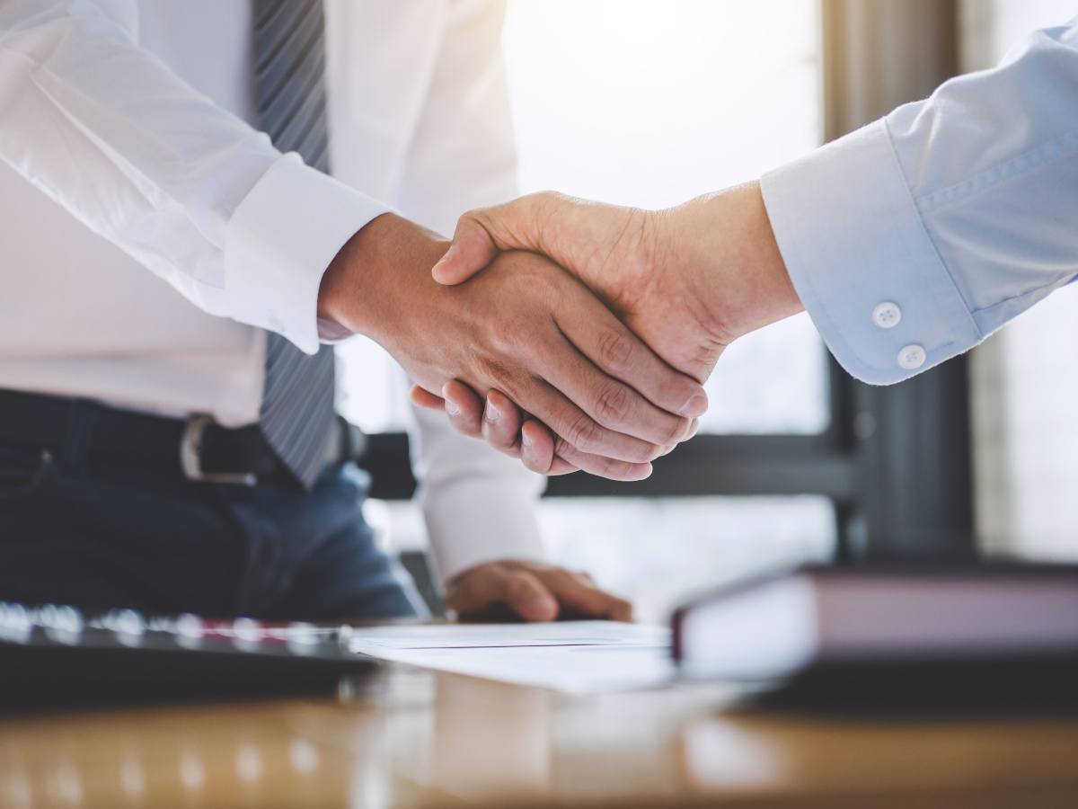 Two business people in office attire, shake hands to signify a deal has been reached.