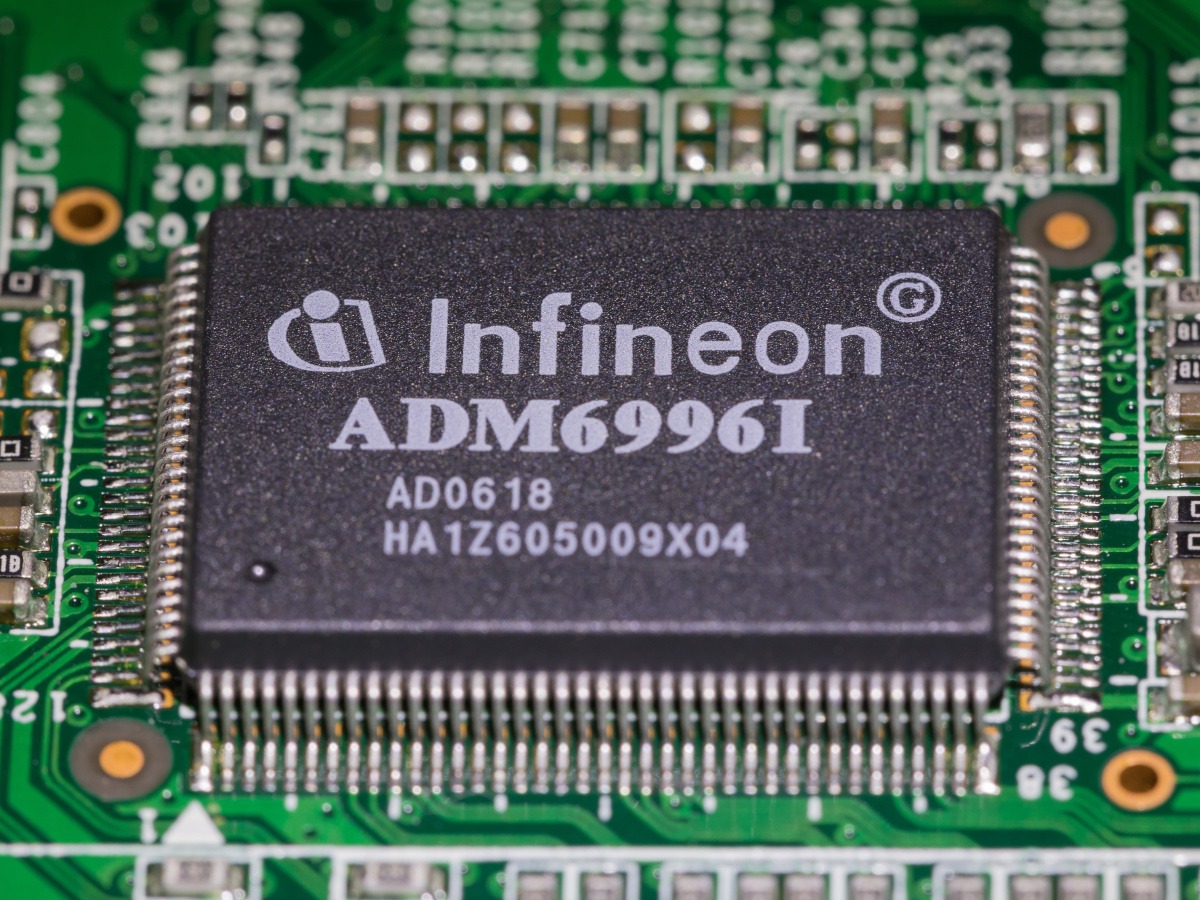 A green chip circuit with a black rectangular piece that has Infineon