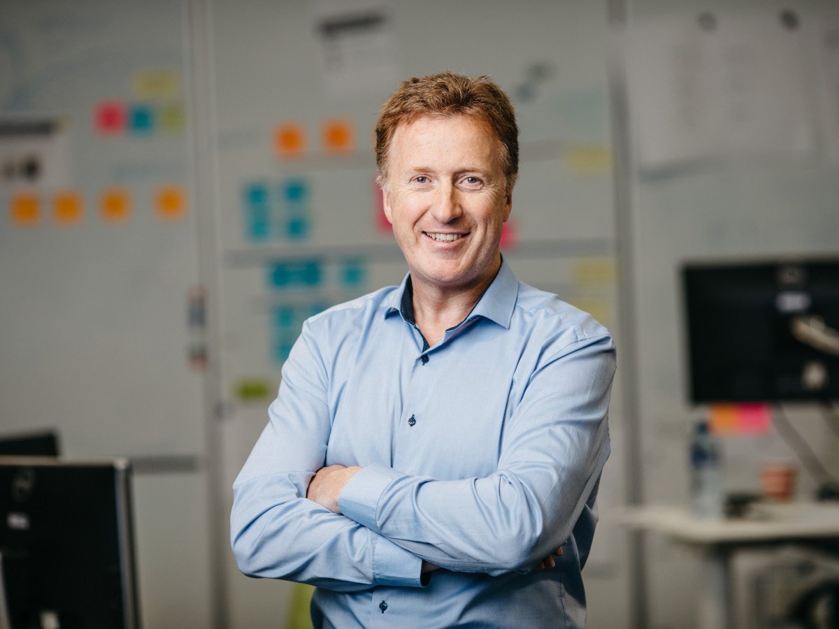 A white, red-haired middle aged man in a blue shirt.