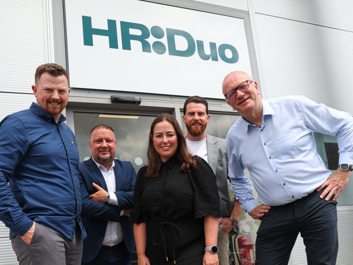 Five people pose and smile outside a HR Duo office.