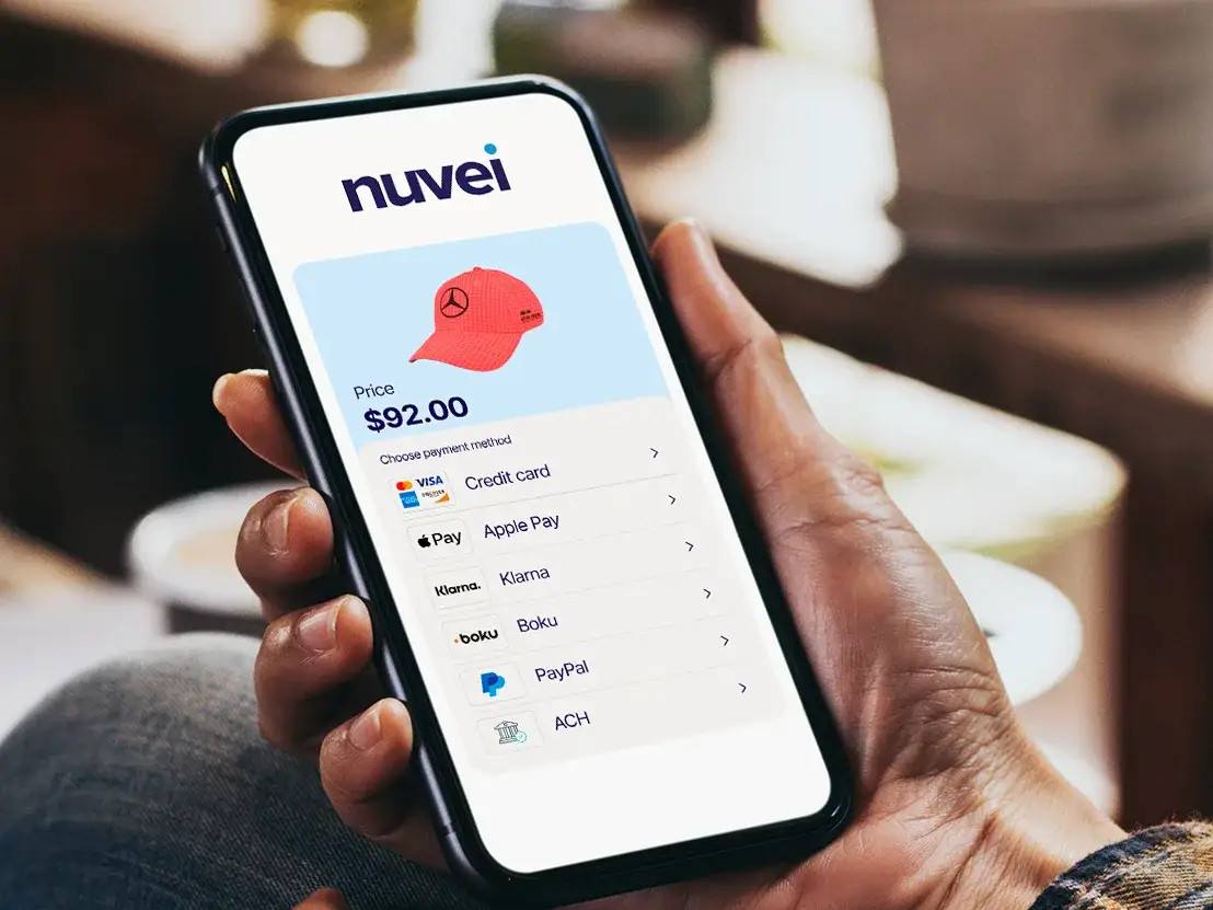 A picture of a smartphone using the Nuvei app to buy a red hat.
