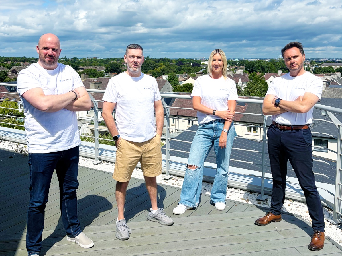 A group of four people in white t shirts standing outdoors during the day.