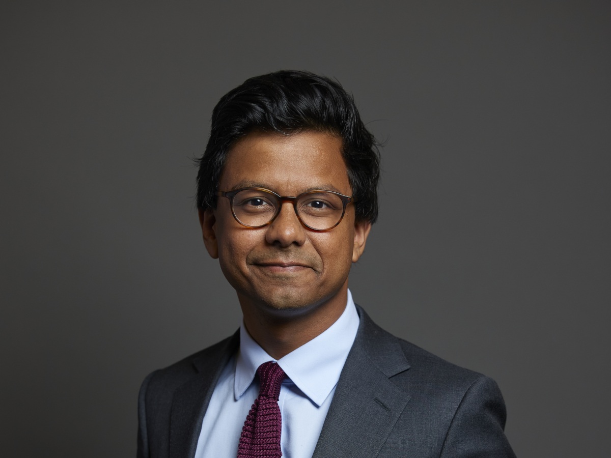 Man of Asian appearance in suit smiles to camera