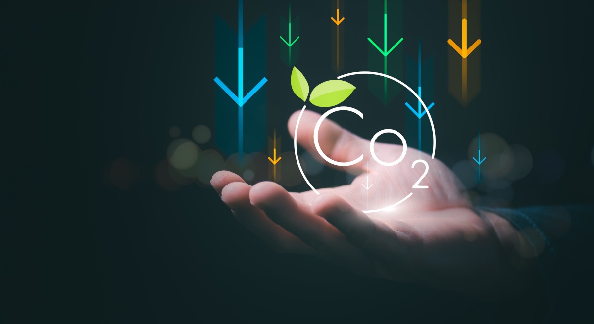 A hand holds up symbols representing greenhouse gas emissions.
