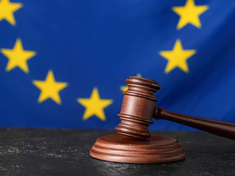 A gavel on a table in front of an EU flag in the background. Used for the concept of the EU