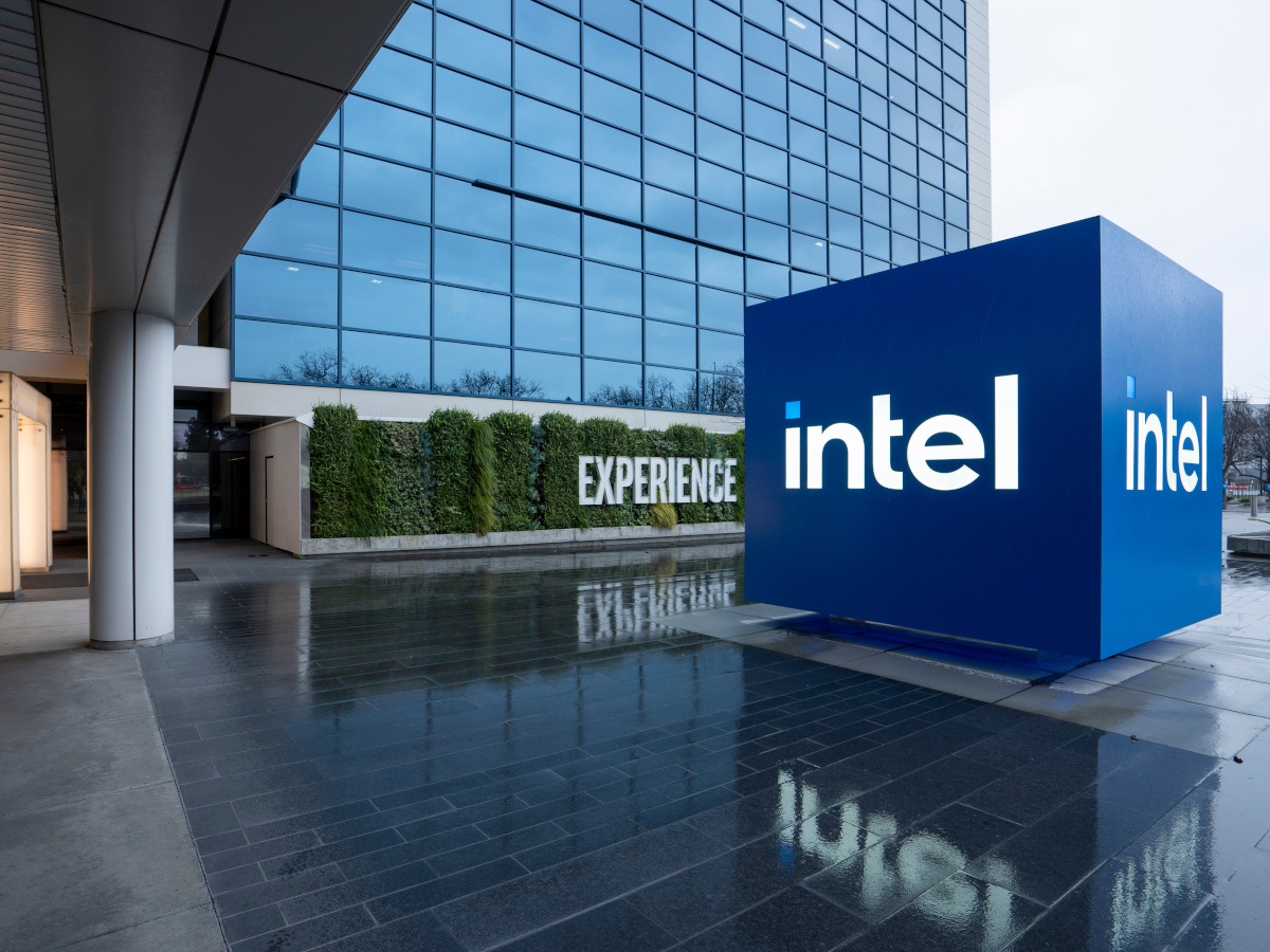 Intel company logo in front of a tall glass building.