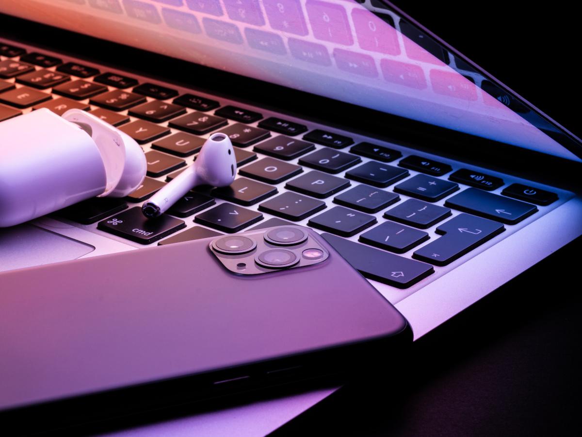 Apple products including an iphone, airpods and macbook placed together.