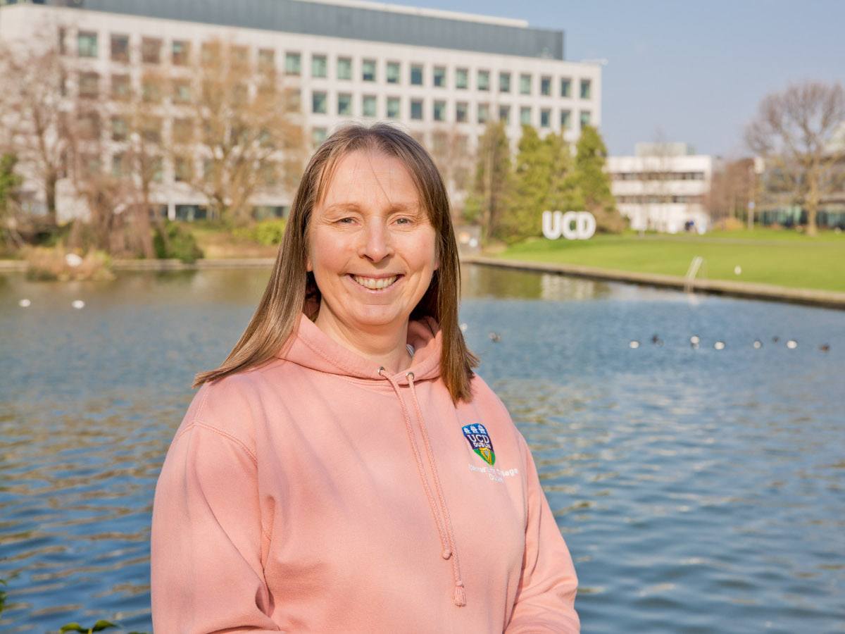 A woman with mousy-brown hair wearing a salmon coloured hoodie.